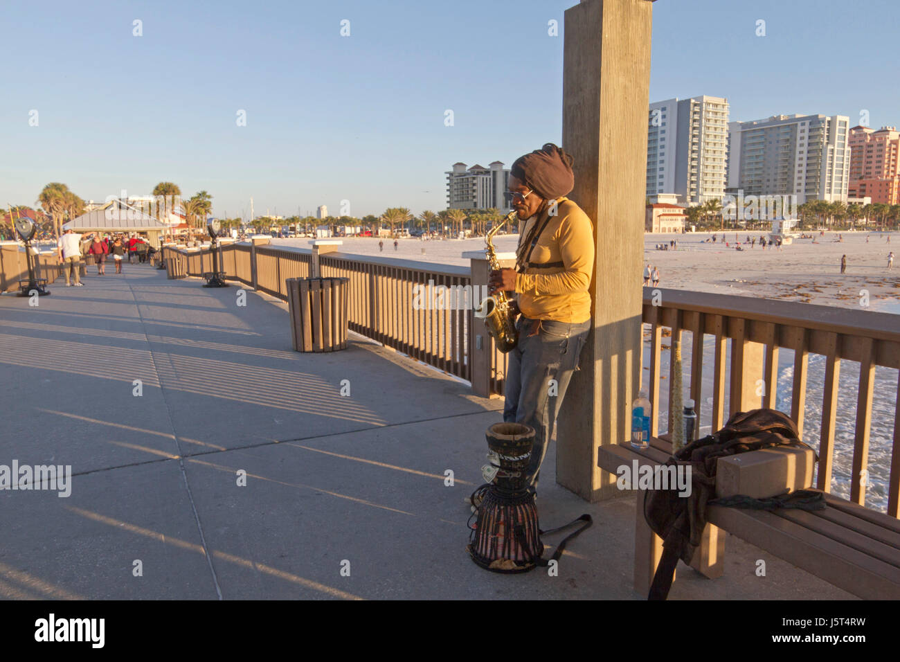 Clearwater Beach; Florida; USA - January 24, 2017:  A busker plays the saxophone for tips as people stoll by around sunset at Pier 60 on Clearwater Be Stock Photo