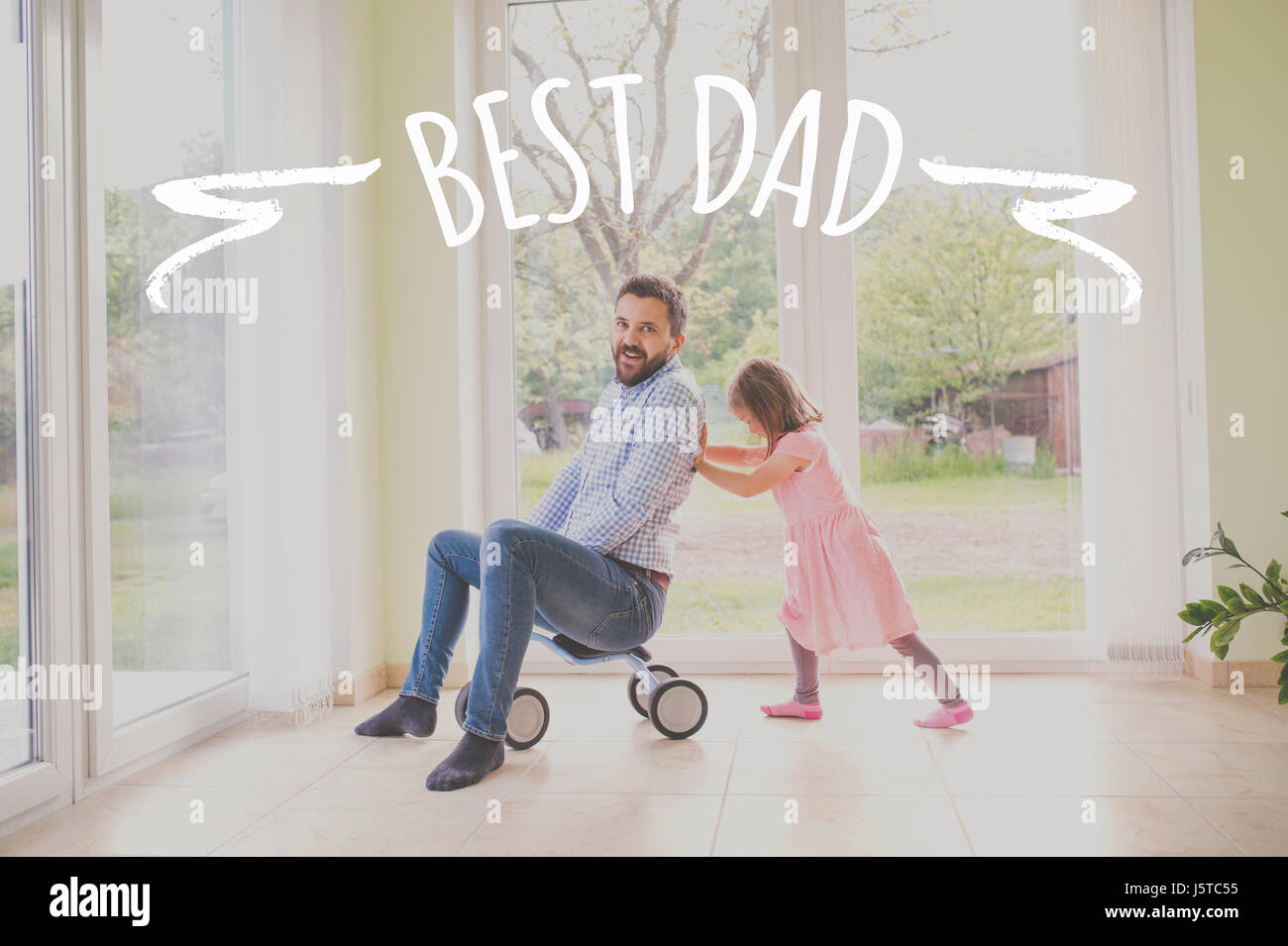 Father and daughter riding bike indoors. Fathers day concept. Stock Photo