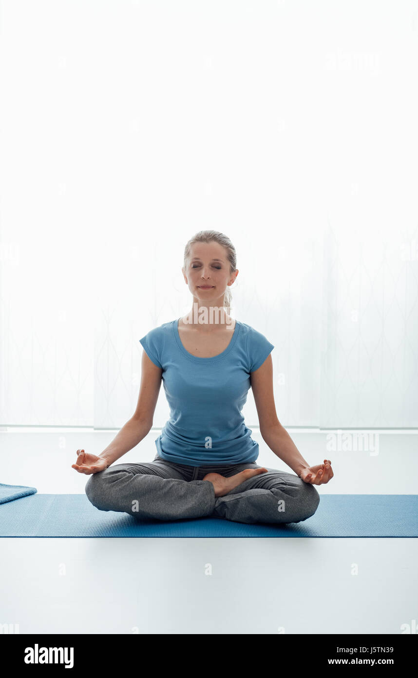 Woman sitting on the floor and doing the lotus position, yoga and ...