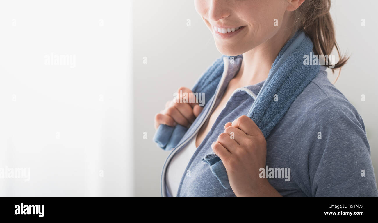 Confident sporty woman smiling at camera and posing with a towel on her ...