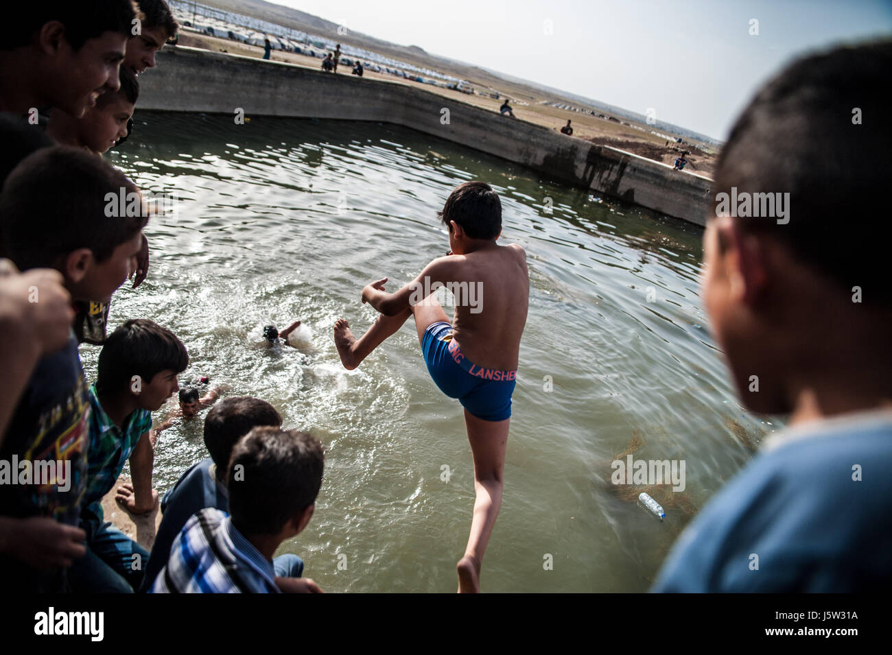Children swim in Hammam Al Alil displacement camp, Iraq Stock Photo