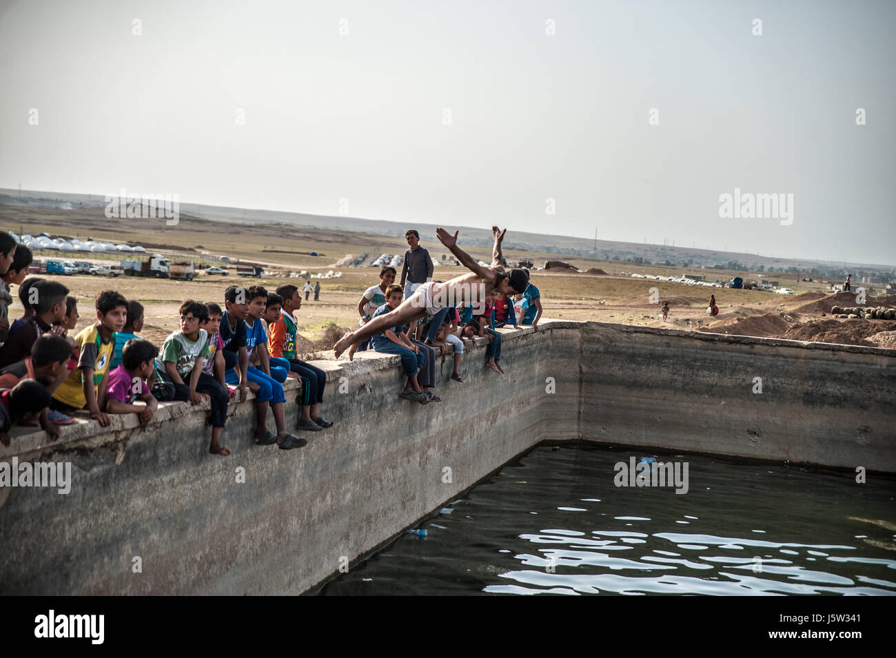Children swim in Hammam Al Alil displacement camp, Iraq Stock Photo