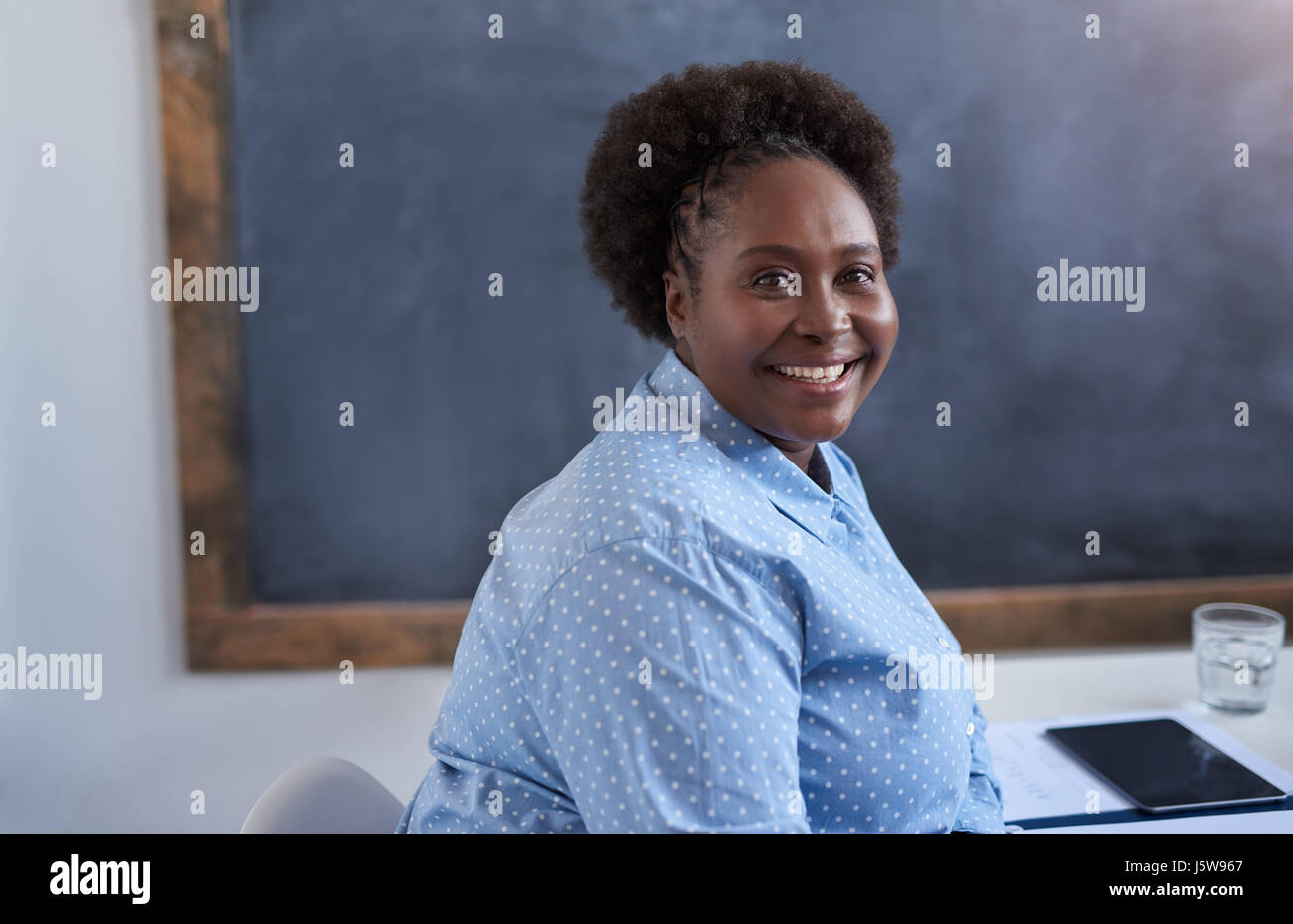 Smiling young African businesswoman sitting in a modern office Stock ...