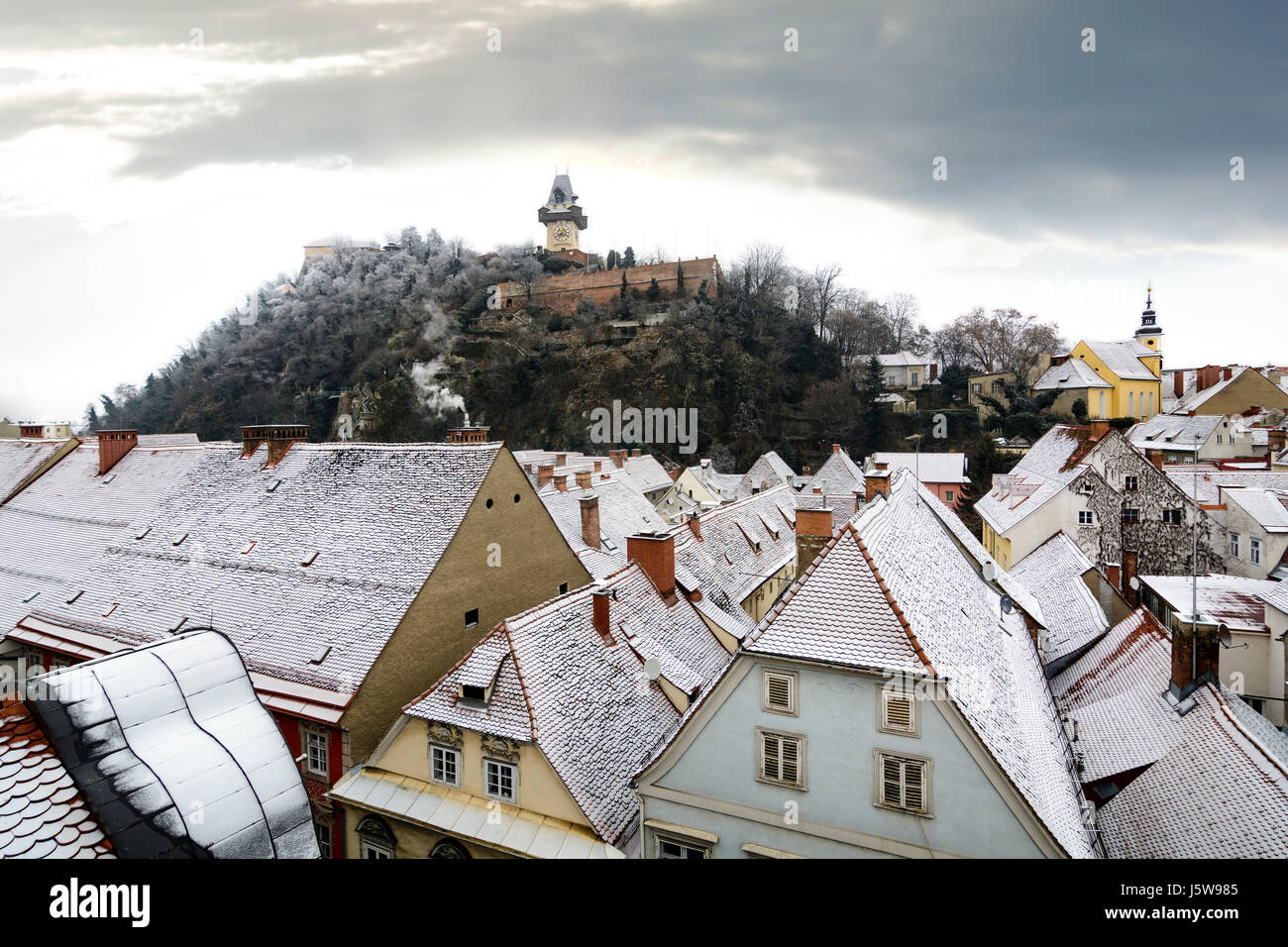 Graz winter scene with clock tower and snowy rooftops Stock Photo