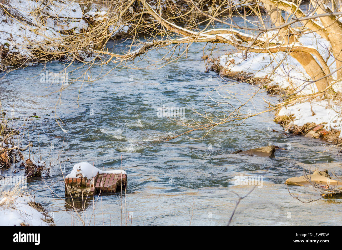 River flowing in winter with landscape of ground and tree covered in ...