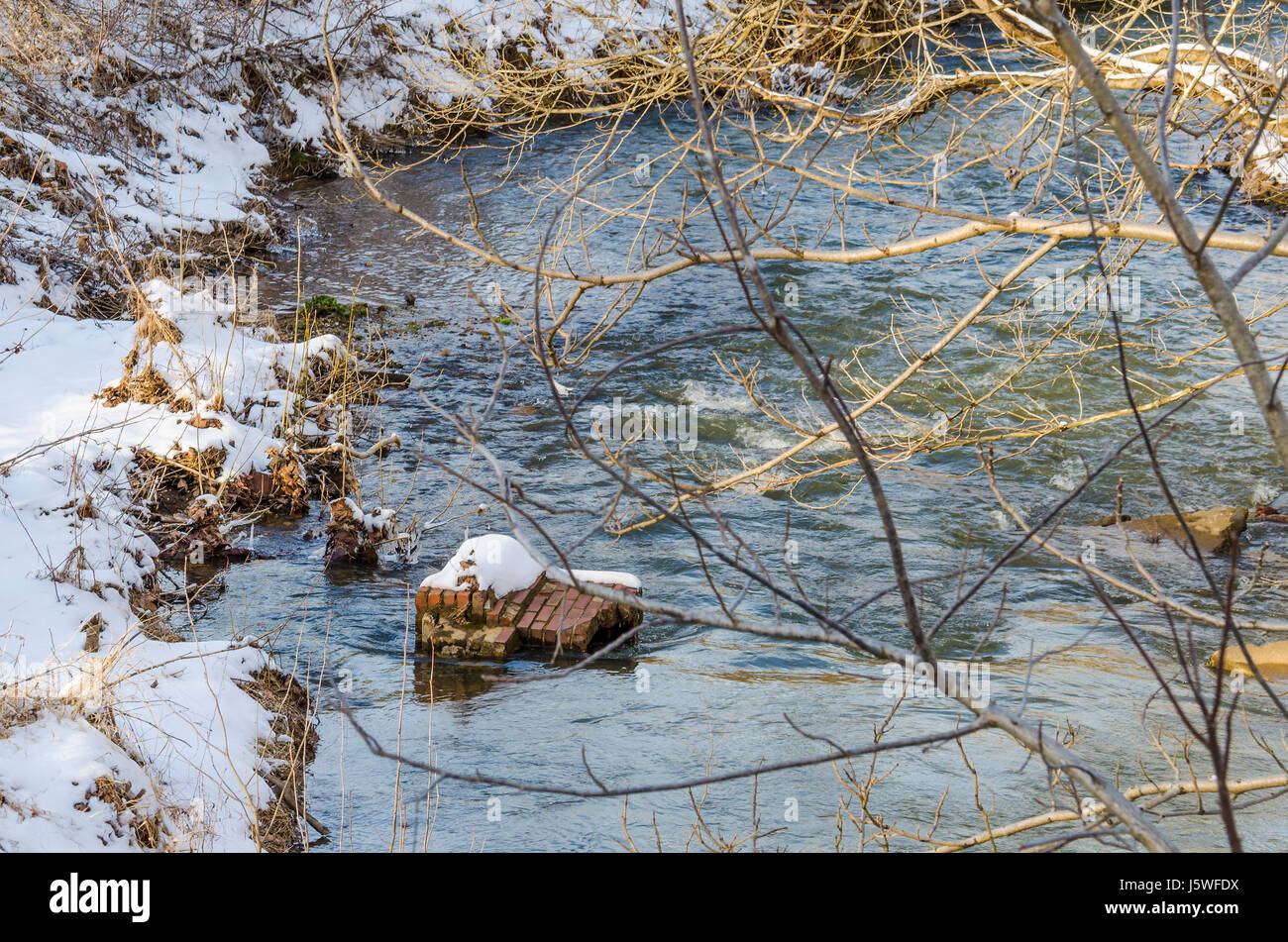 River flowing in winter with landscape of ground and tree covered in ...