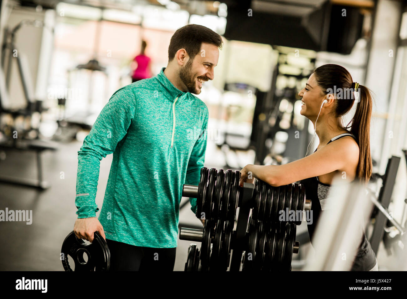 Young woman exercise in a gym with the help of her personal trainer ...