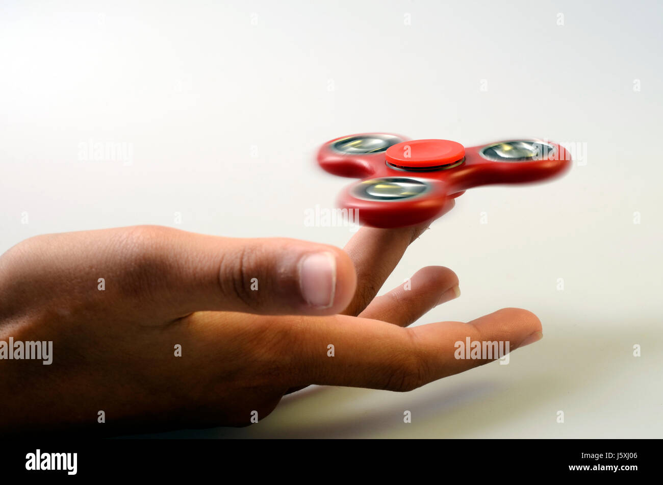 red Hand spinner, fidgeting hand toy rotating on child's finger Stock
