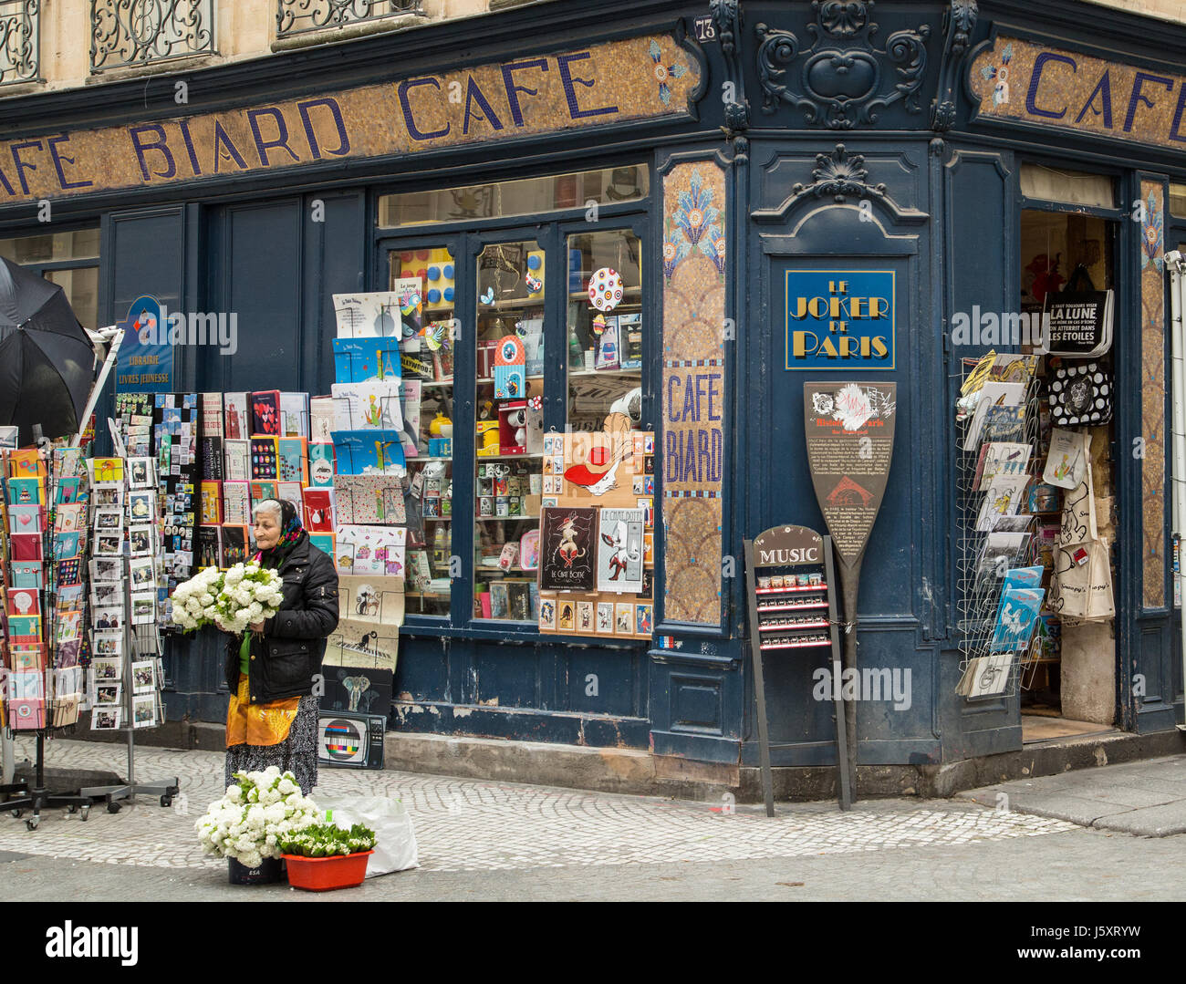 An old woman sells flowers on the street outside Cafe Biard in Paris