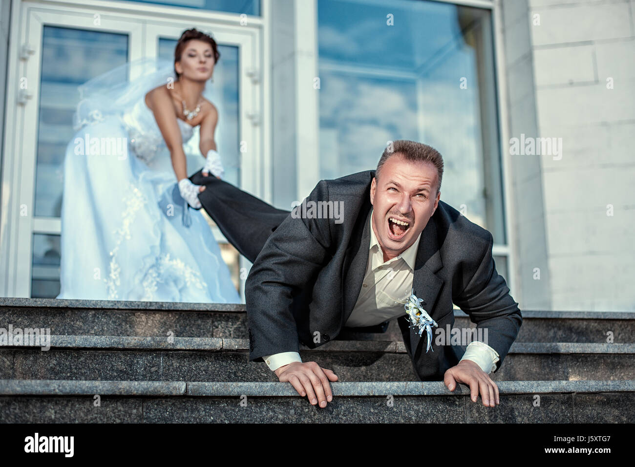 Bride leg pulls groom at the wedding. Stock Photo