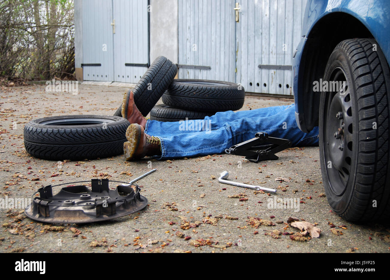 chaos layman change of tyres hub cap tyre tire tyres exhausted man make tool Stock Photo