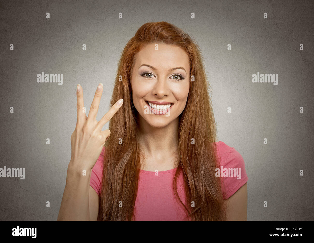 Closeup portrait young woman giving three fingers gesture with hand isolated grey background
