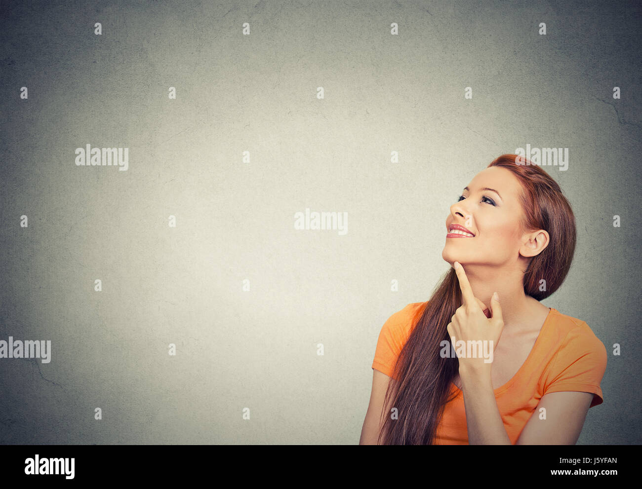 Portrait happy beautiful woman thinking looking up isolated grey wall ...