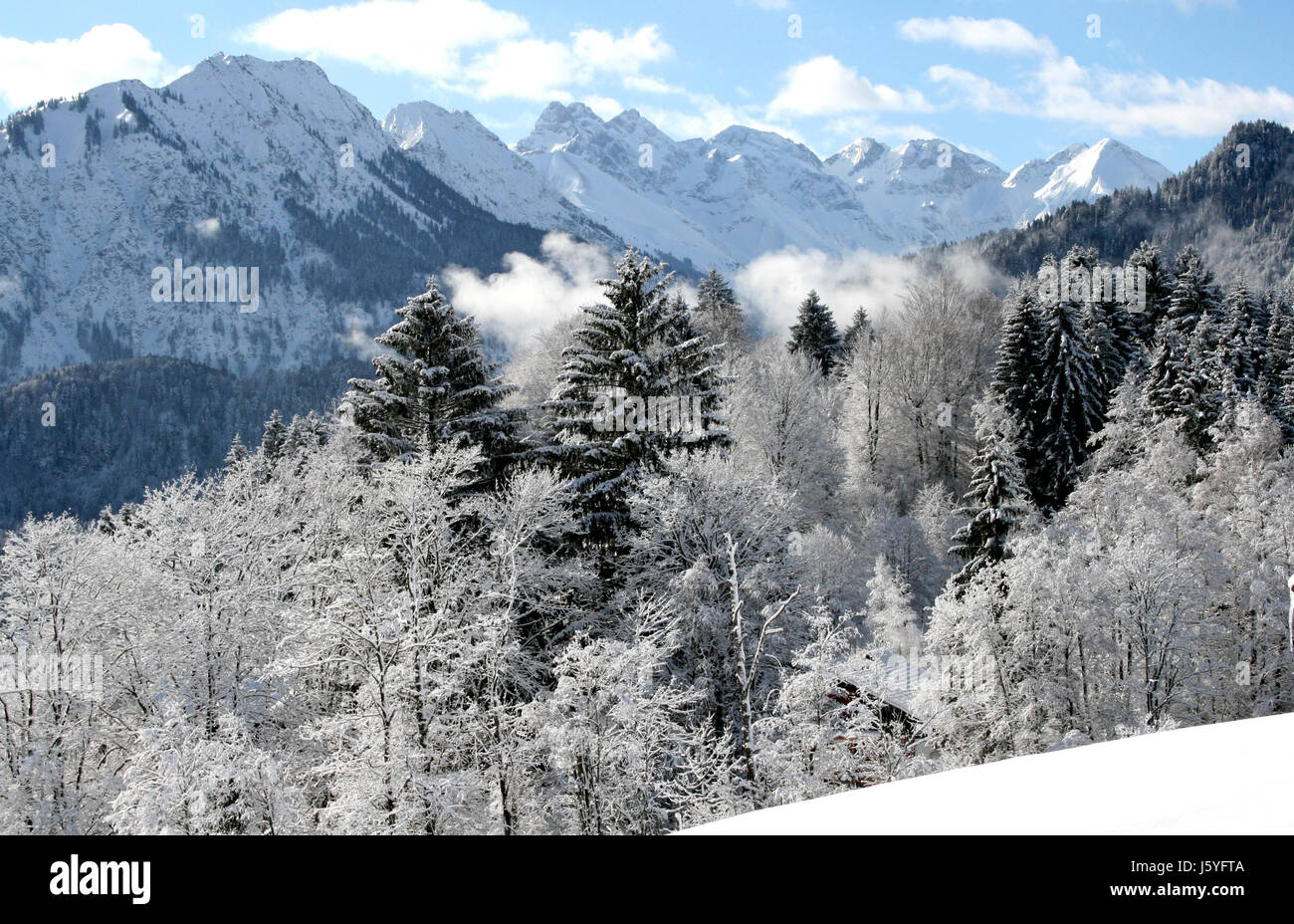 mountains fog bavaria snowcapped snow clouds shine shines bright lucent light Stock Photo