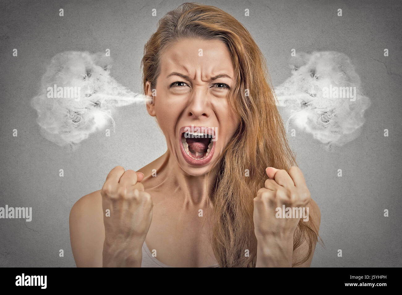 Closeup portrait angry young woman blowing steam coming out of ears, having nervous atomic breakdown, screaming isolated grey wall background. Negativ Stock Photo
