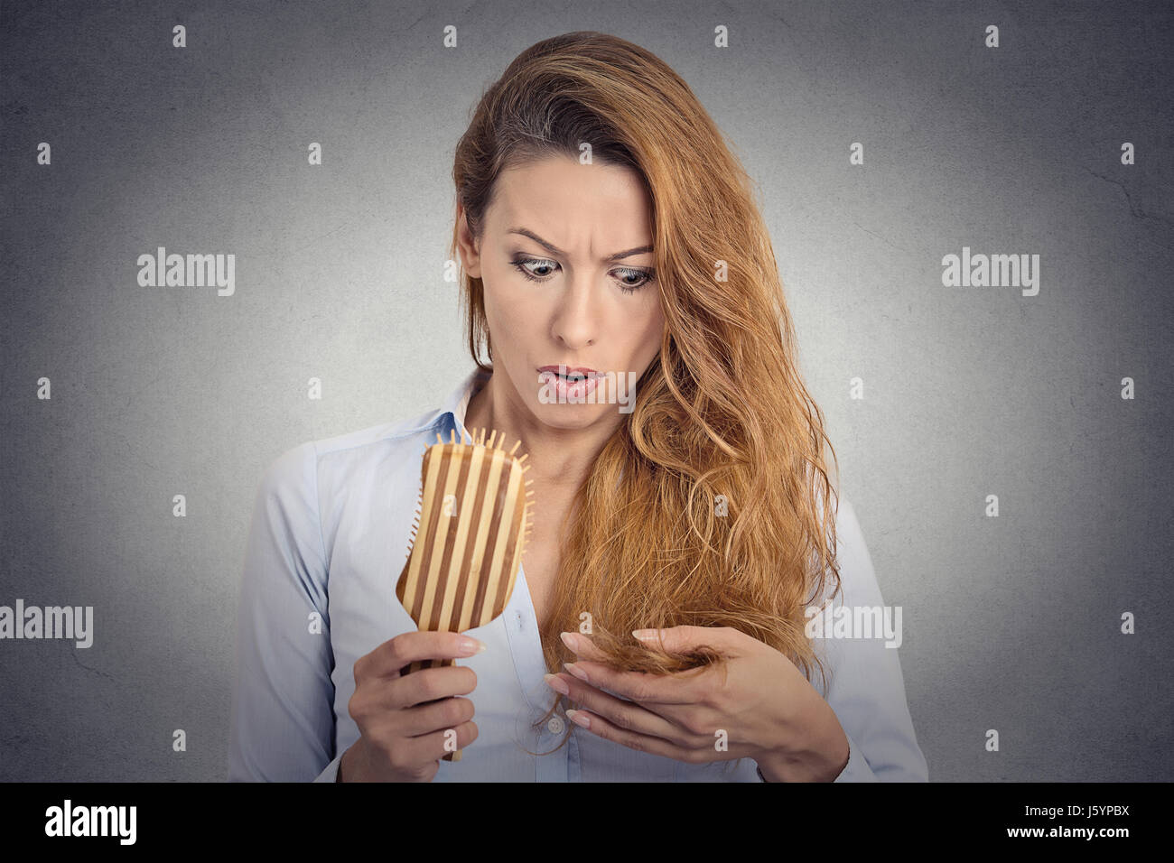 Portrait upset woman combing surprised she is losing hair, receding hairline. Face expression emotion Stock Photo