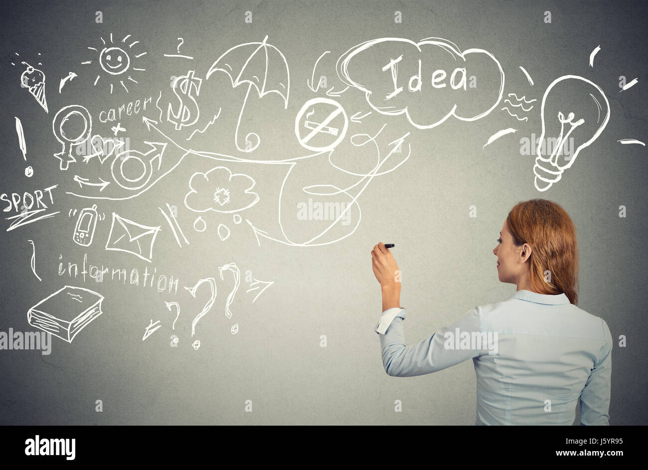 Back side view business woman writing with pen many ideas on grey wall blackboard planning future. Perception vision priorities career personal life b Stock Photo