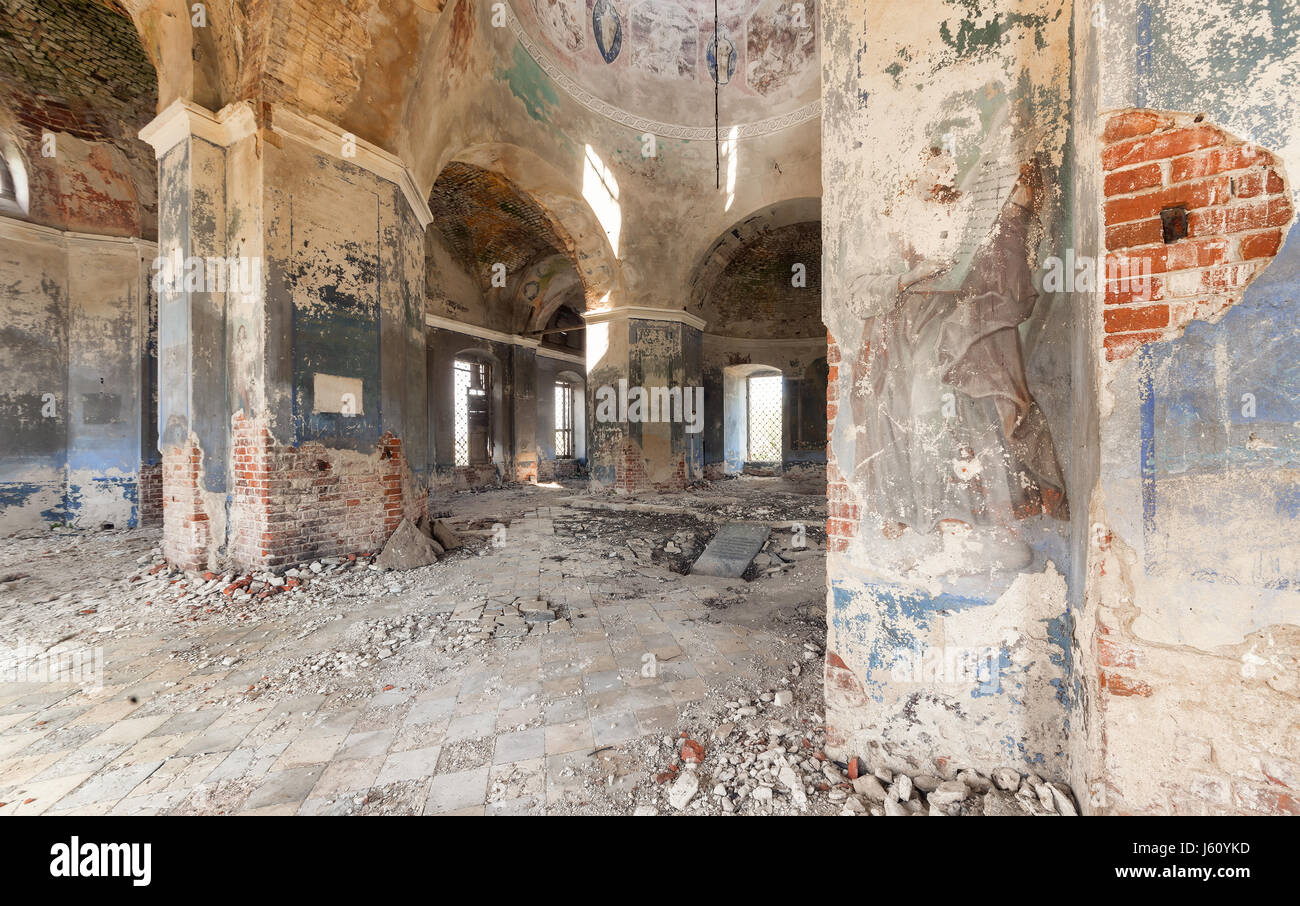 Inside an abandoned looted temple. Columns and a dome with crumbling paint and plaster Stock Photo