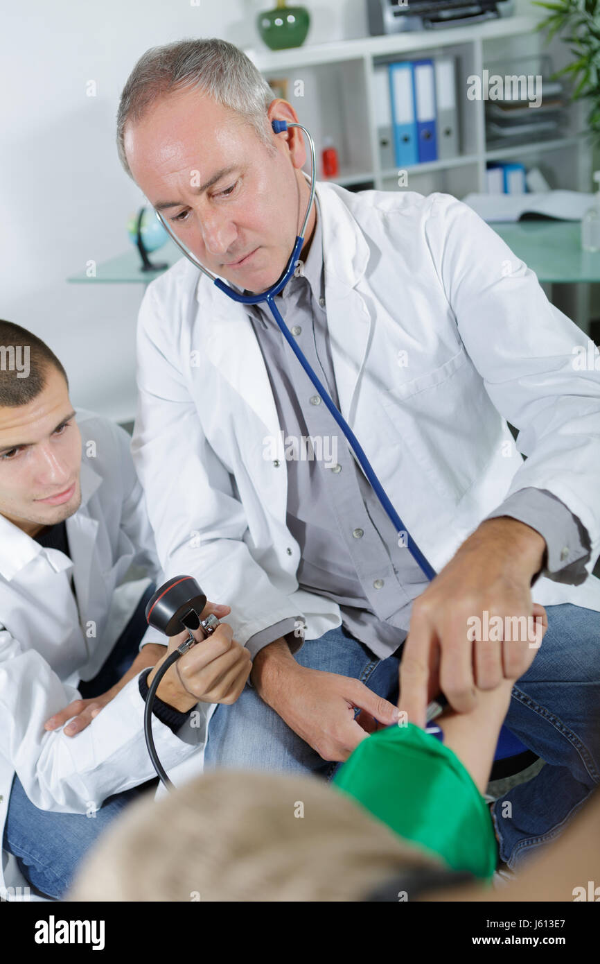 Male doctor taking blood pressure with student Stock Photo