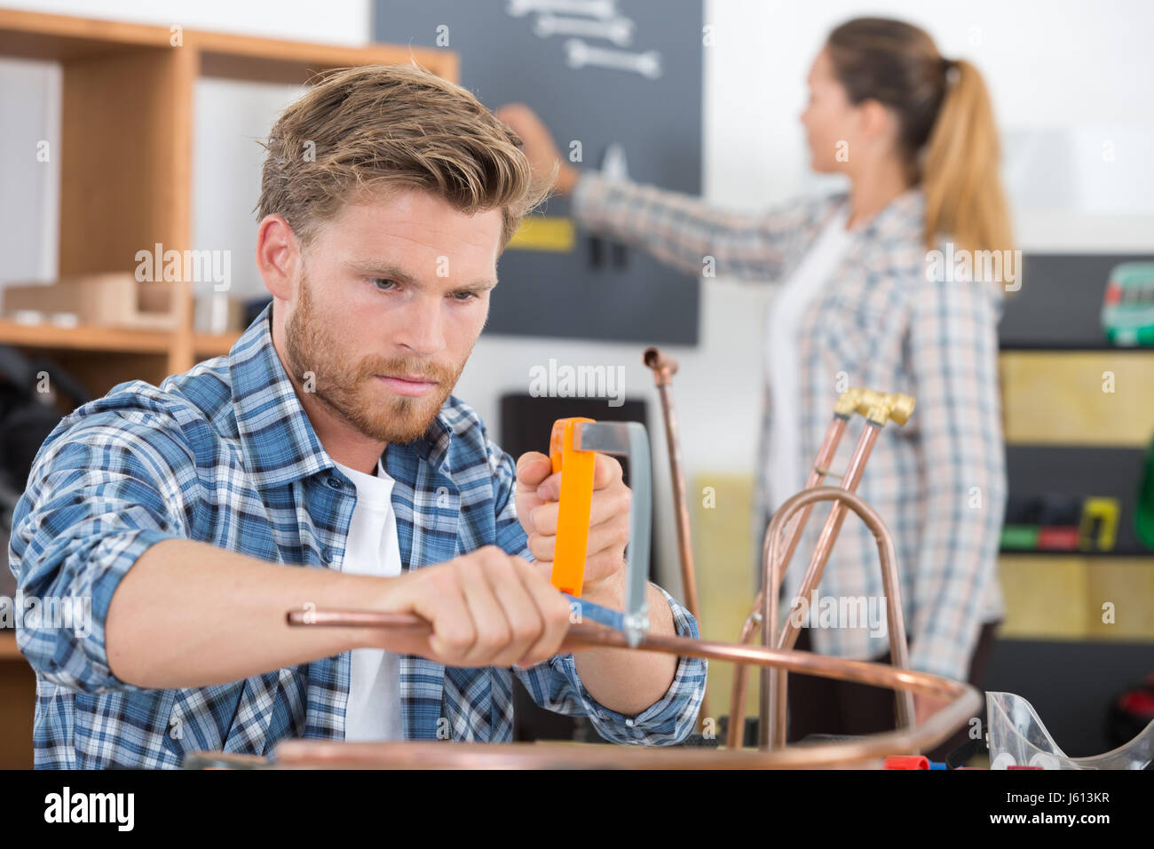 Tradesman cutting copper pipe with hacksaw Stock Photo Alamy