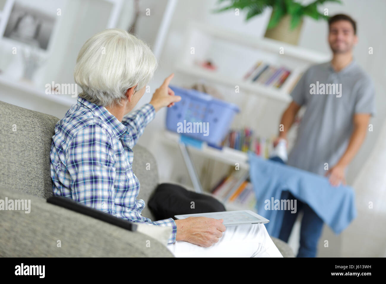 Elderly lady talking to man ironing Stock Photo - Alamy