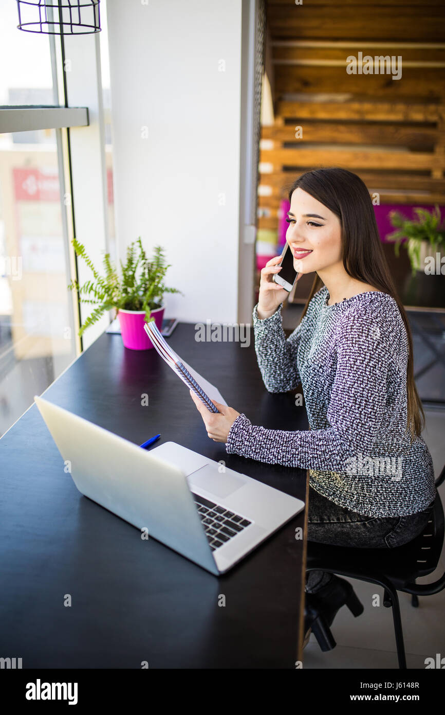 Freelancer female working talking on the phone and browsing in a laptop ...