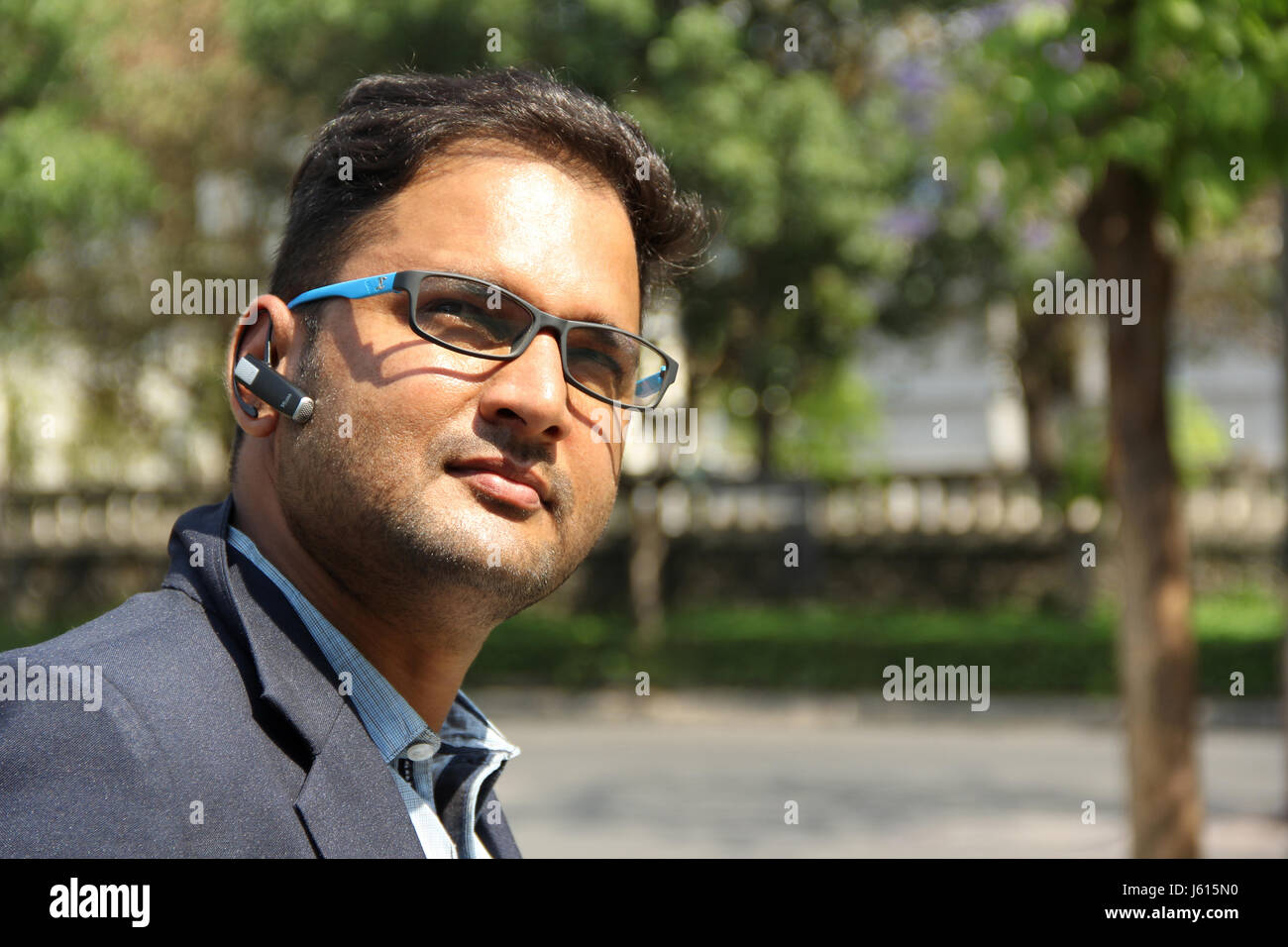 Young Indian corporate man with Bluetooth headset dreaming, thinking Stock Photo