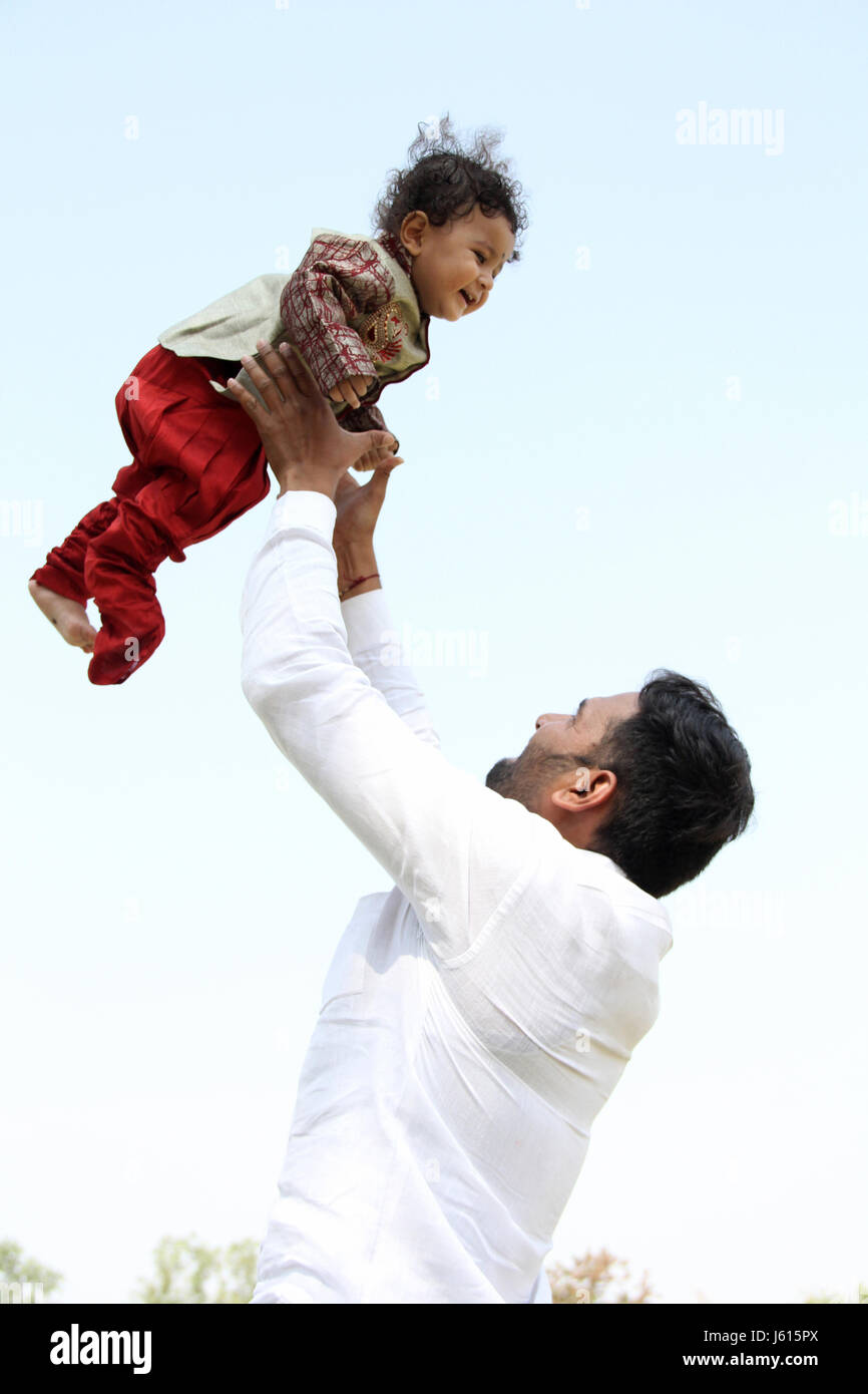 Young Indian father playing with toddler by throwing him in the air Stock Photo
