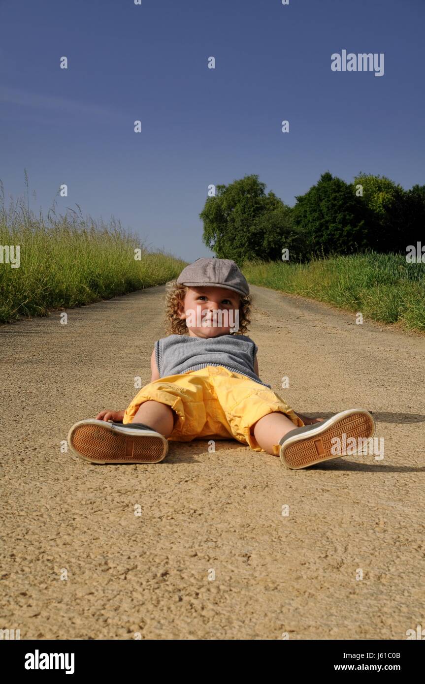 dirt road relaxed lie lying lies outstretched child blue laugh laughs