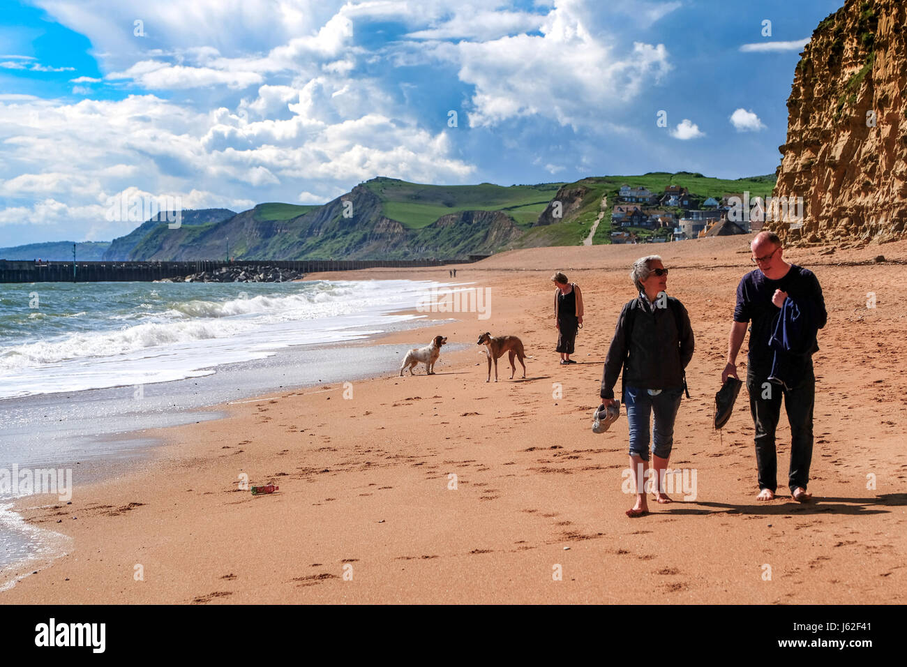 West Bay, Dorset, UK. 19 May 2017. People enjoy a walk on the beach as the sunshine and warm weather returns to the Dorset Coast. Credit: Tom Corban/Alamy Live News Stock Photo