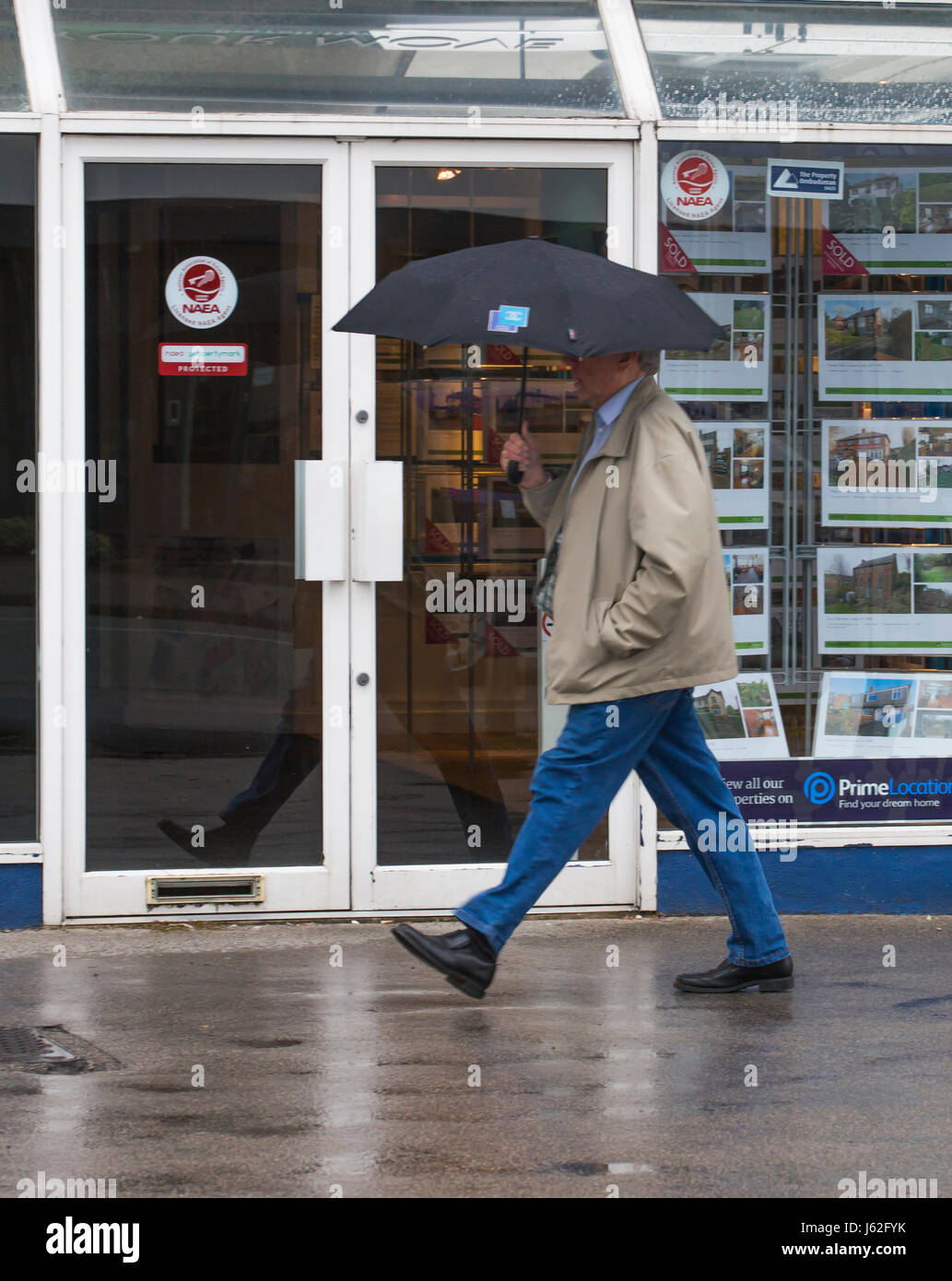 Leeds, UK. 19th May, 2017. A man walking in front of estate agents