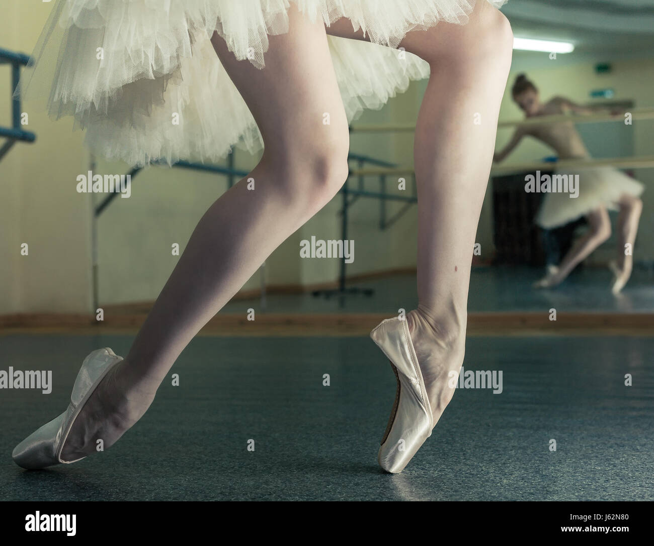 Ballerina in pointe shoes and a pack stands on the fingers of the machine. Reflection in the