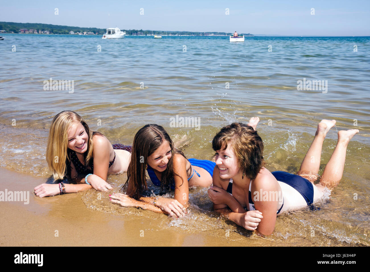Michigan Traverse City,West Arm Grand Traverse Bay,Clinch Park,three girls,teen,teens,bikini,soak,immerse,water,public,beach,fun,wateractivity,friends Stock Photo