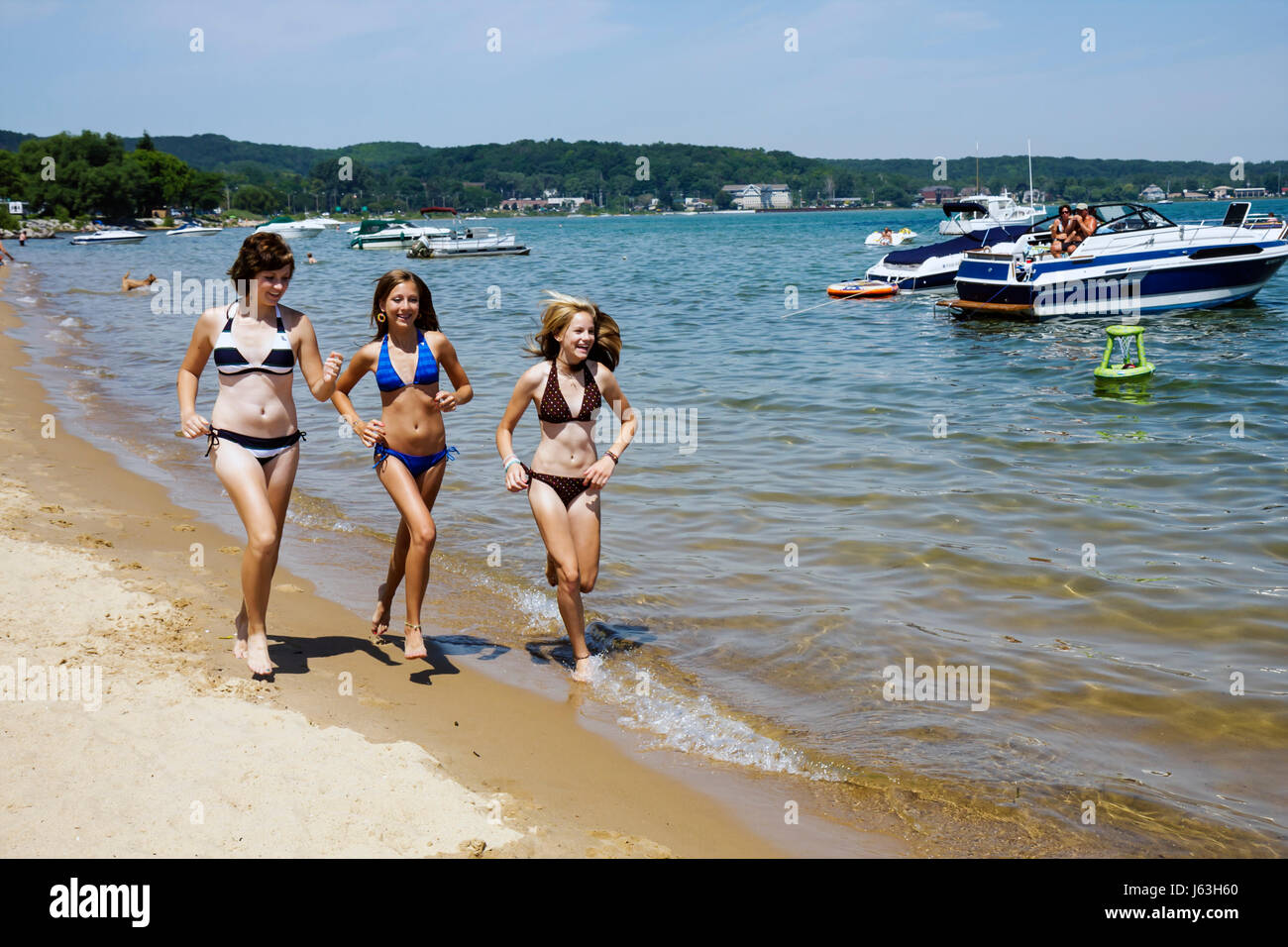 Traverse City Michigan,West Arm Grand Traverse Bay water,Clinch Park,three girls,teen,teens,bikini,jog,run,shoreline,tan,public,beach beaches,anchored Stock Photo