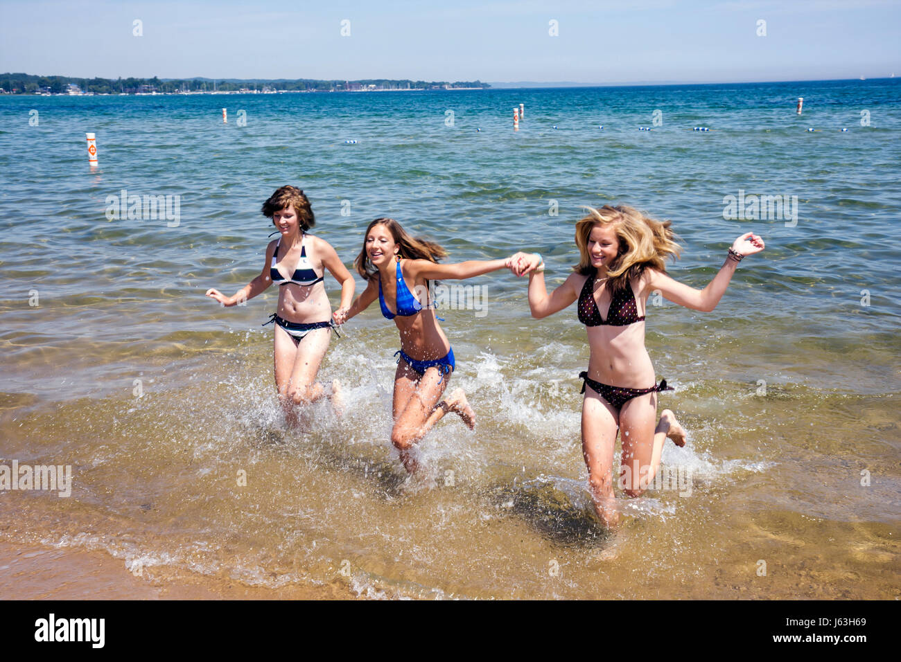 Traverse City Michigan,West Arm Grand Traverse Bay water,Clinch Park,three girls,teen,teens,bikini,splash,water,public,beach beaches,fun,recreation,ac Stock Photo