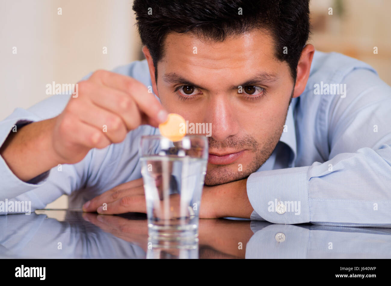 Handsome man dropping effervescent tablet in glass of water Stock Photo