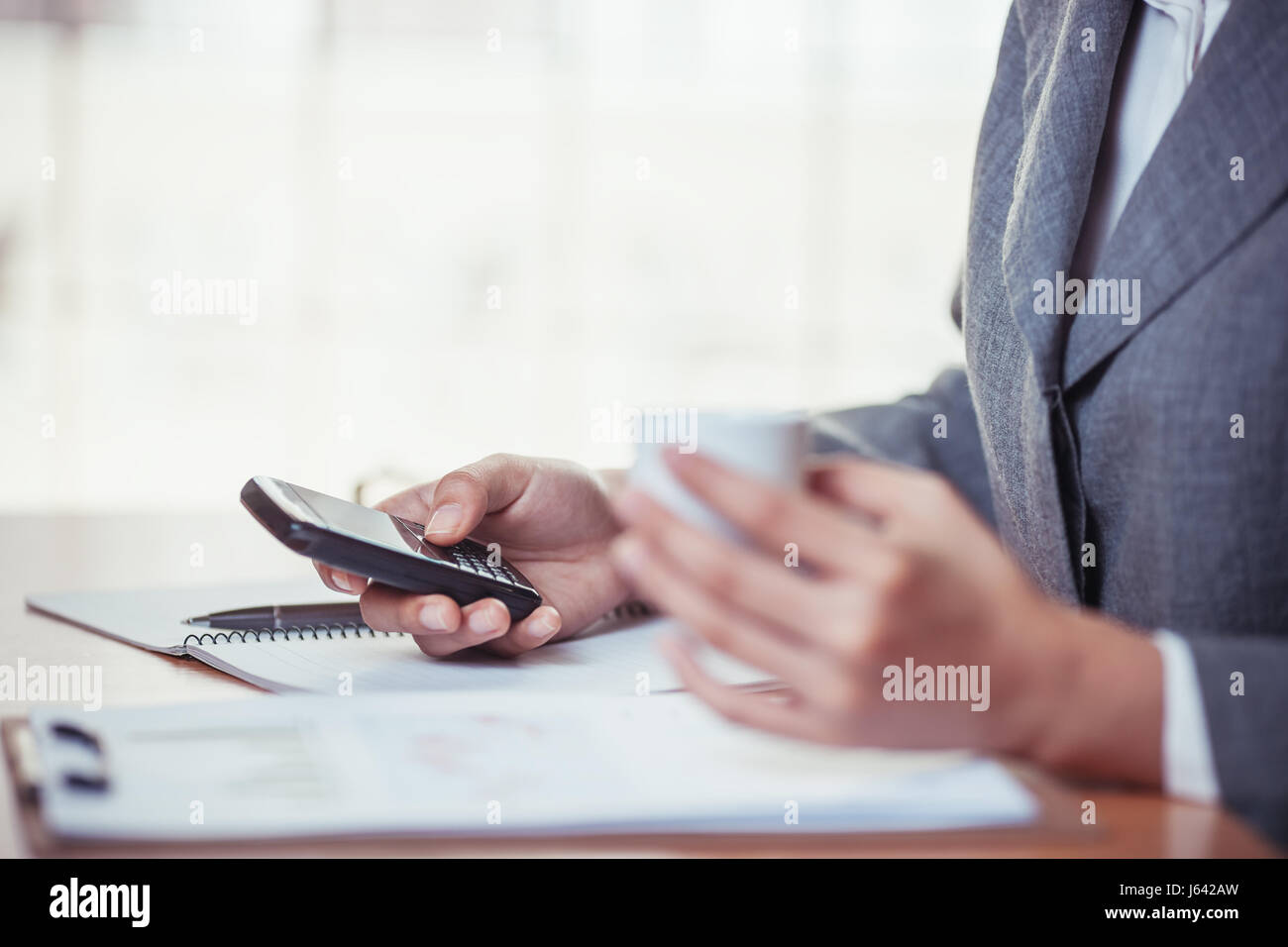Businesswoman surf internet on smartphone and holding coffee cub Stock Photo
