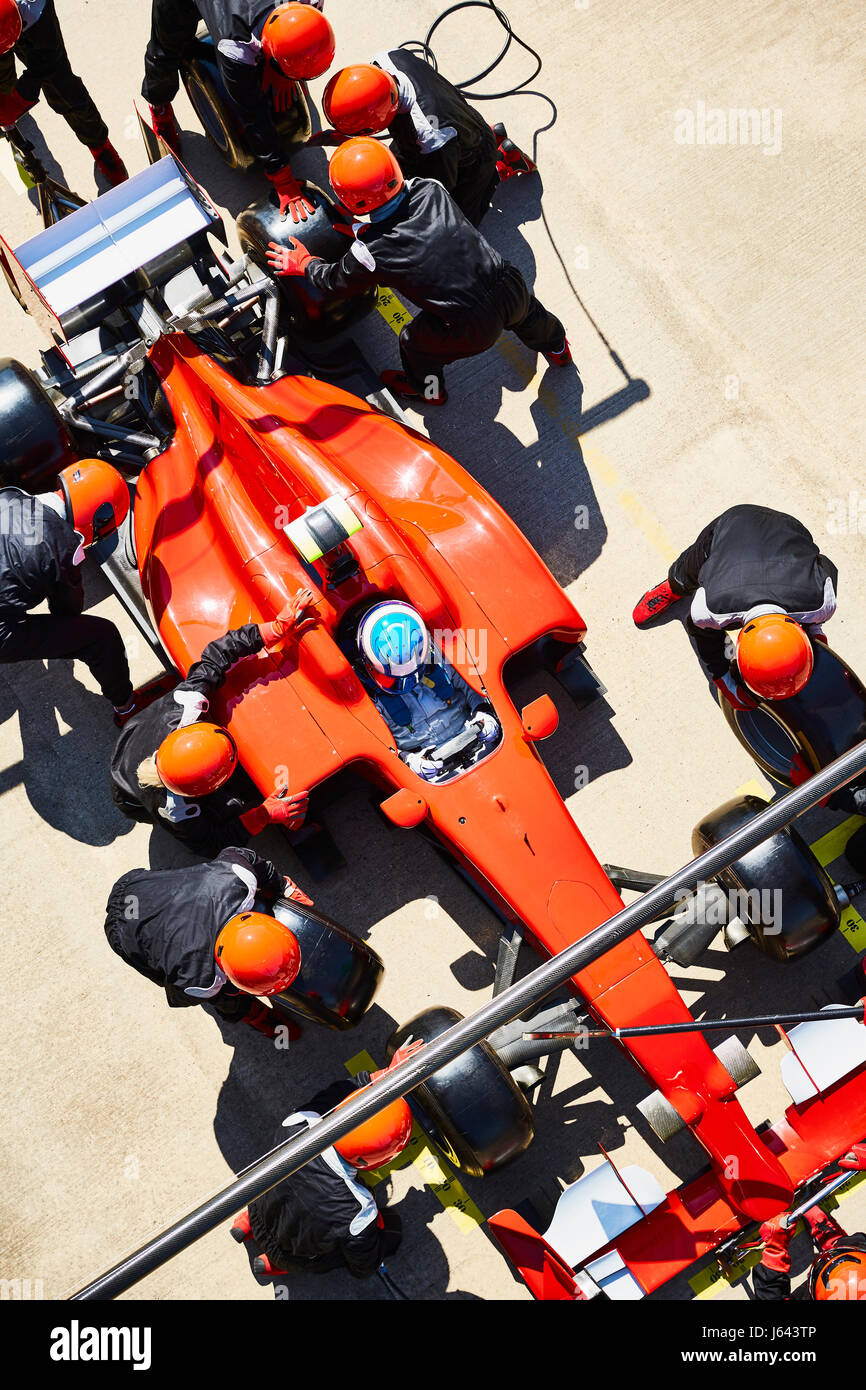 Overhead pit crew replacing tires on formula one race car in pit lane