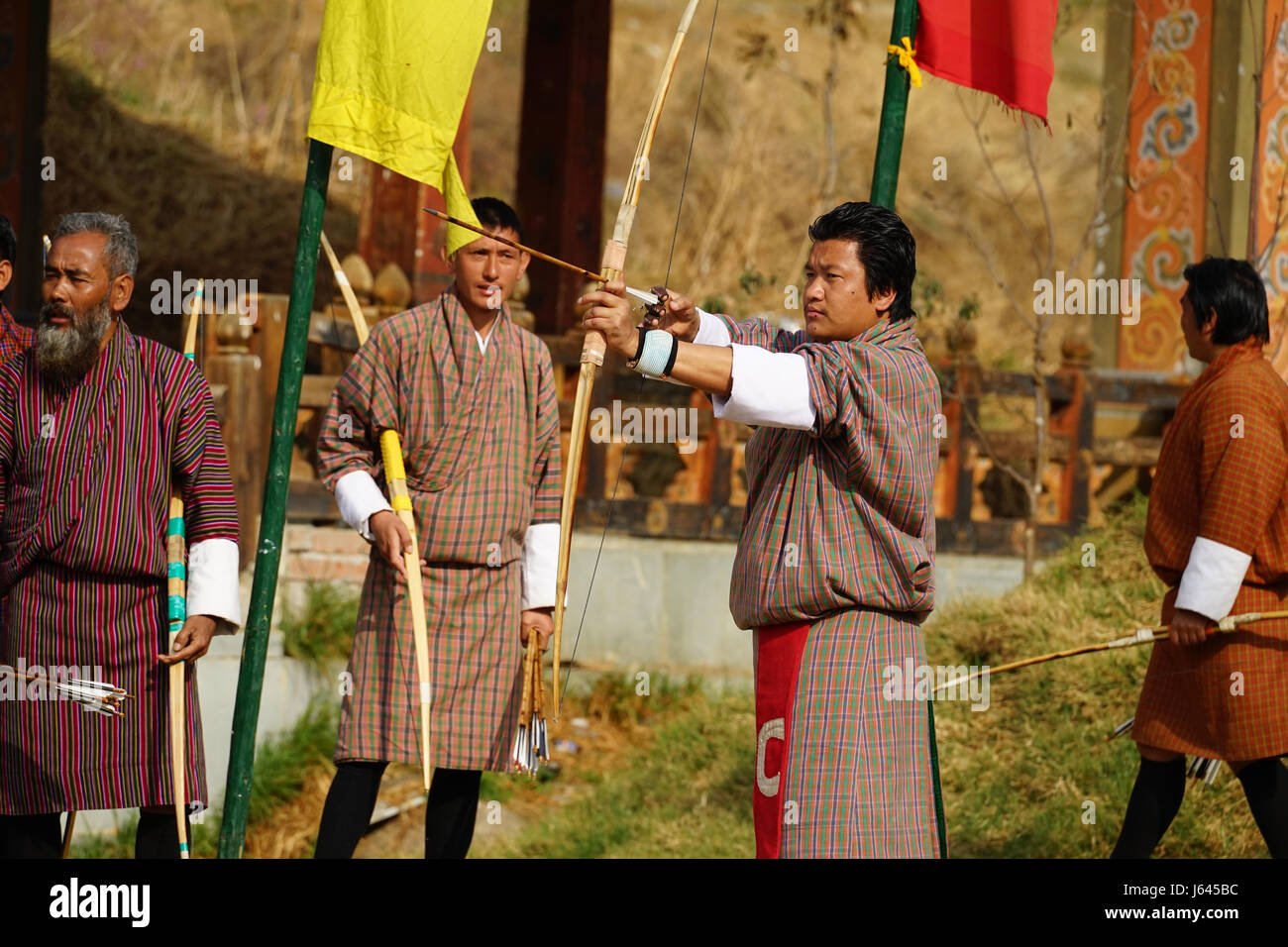 Man in traditional clothing shooting with bow an arrow at Thimphu, Bhutan Stock Photo