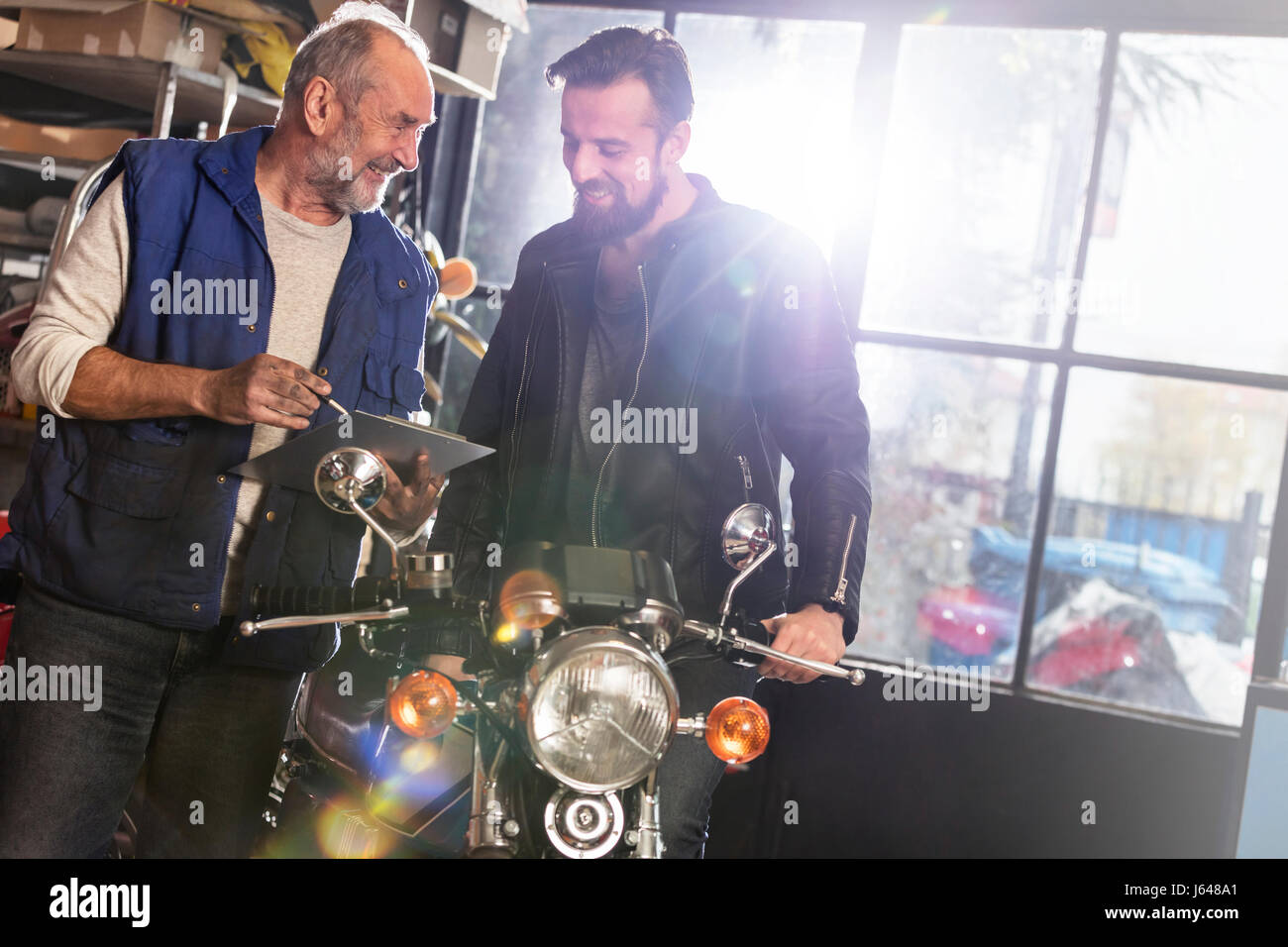 Motorcycle mechanic discussing paperwork with customer in shop Stock Photo