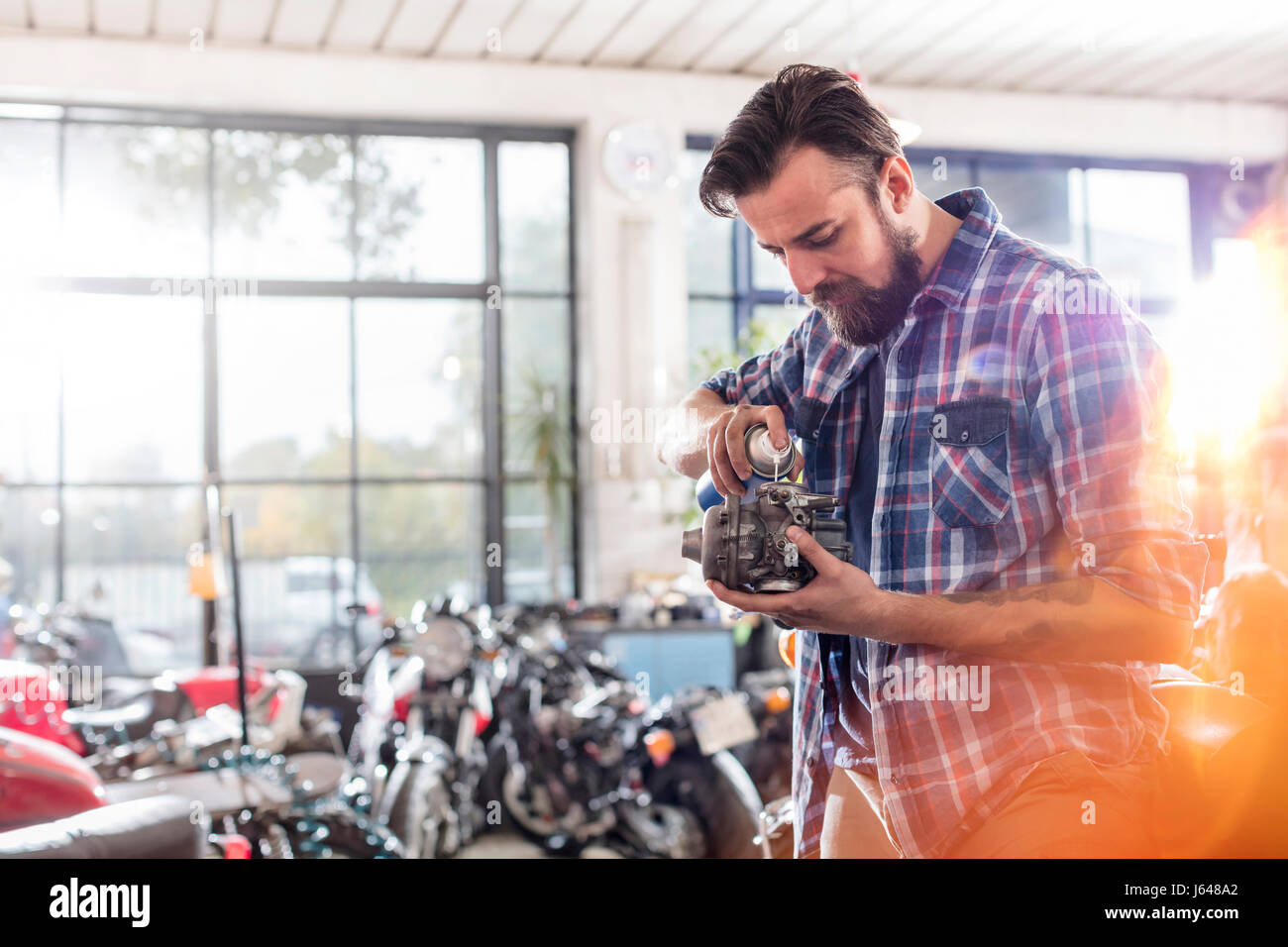 Motorcycle mechanic greasing engine part in workshop Stock Photo