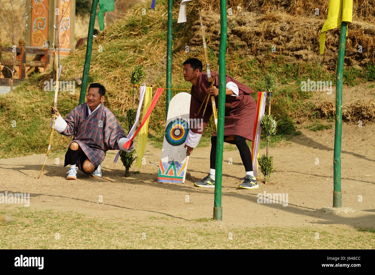 Men in traditional clothing showing hit on target at bow an arrow shooting in Thimphu, Bhutan Stock Photo