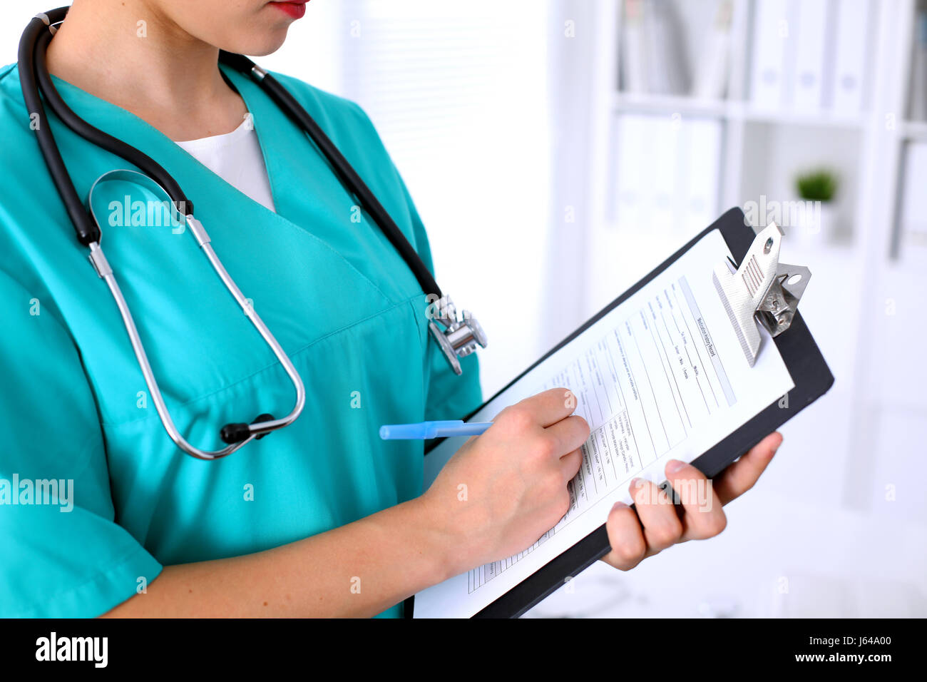Close-up of a female doctor is filling out application form or medical ...