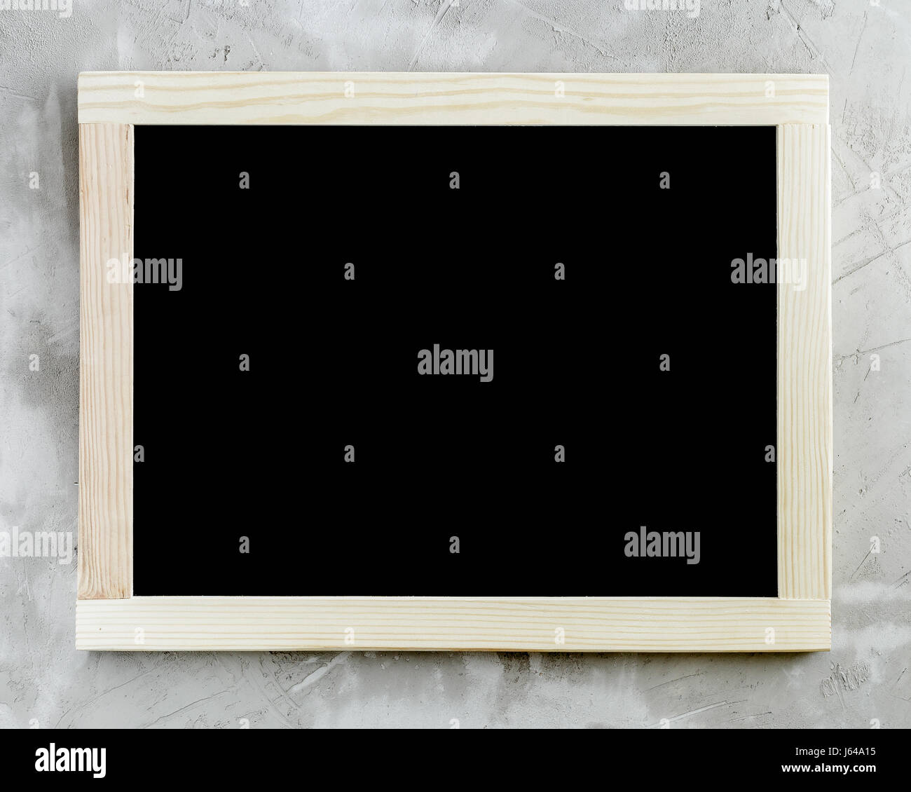 Blank black chalkboard with wooden frame on concrete background. Stock Photo