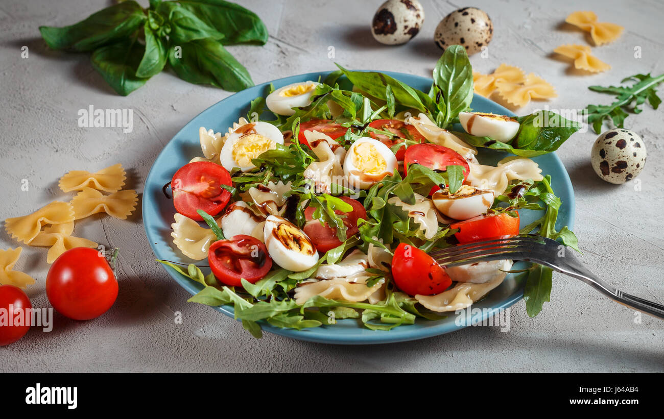 Farfalle bow tie pasta salad with quail eggs, cherry tomatoes, rucola