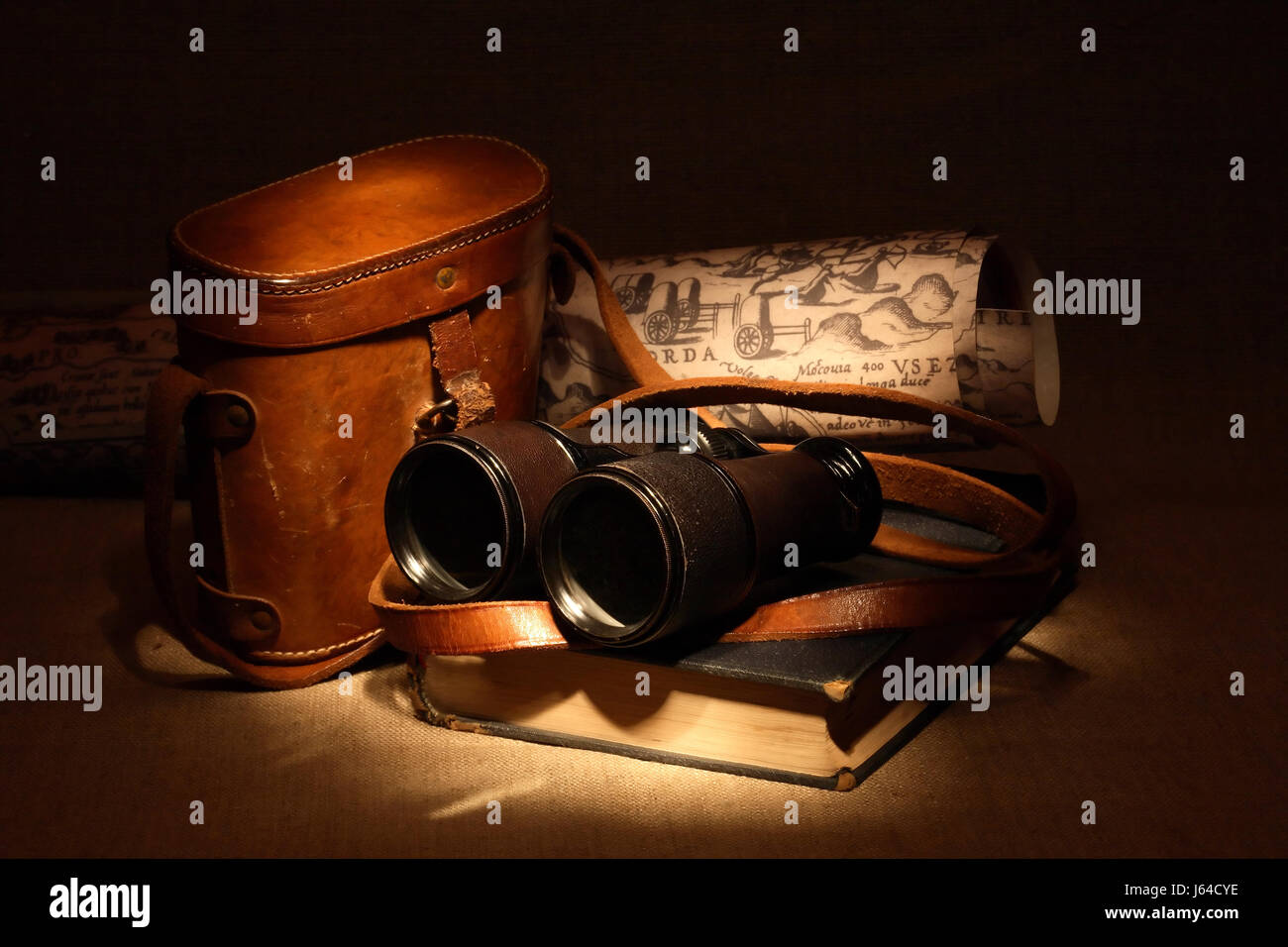 Still life with old binoculars on ancient book near leather case Stock Photo