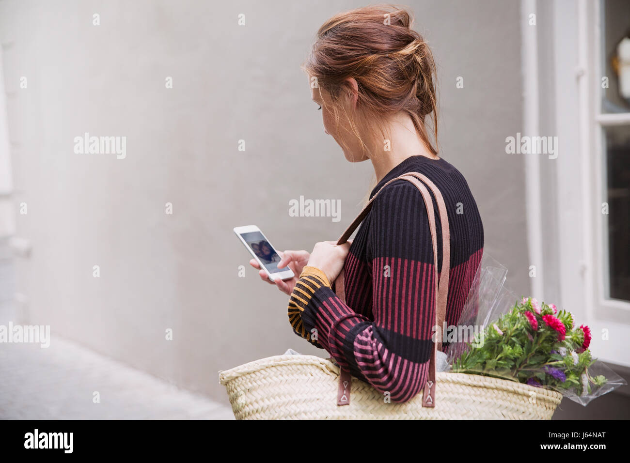 Woman video chatting with cell phone in alley Stock Photo