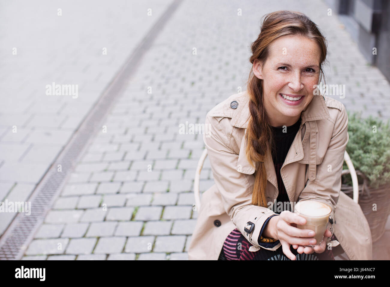 Portrait smiling woman drinking iced coffee at sidewalk cafe Stock Photo
