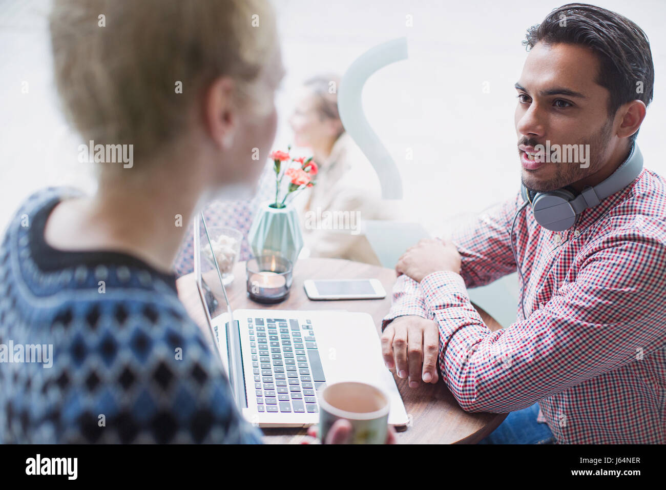 Young man and woman talking at laptop in cafe window Stock Photo