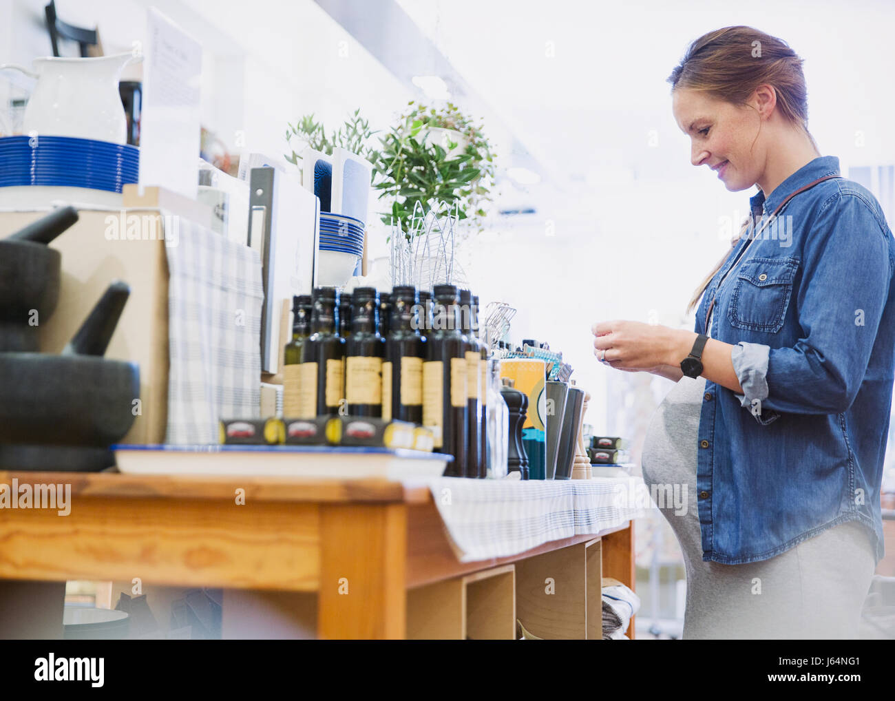 Pregnant woman shopping, browsing olive oil in shop Stock Photo
